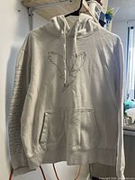 Front view of off-white hoodie showing eagle design on chest and AMERICAN EAGLE text on sleeve.