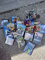 Photo of a bundle of kids DVDs on concrete ground showing various animated and live-action movie covers.