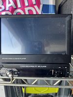 Front view of the car stereo showing the 7-inch screen and control panel with volume knob and input ports.