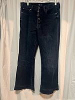 Full front view of dark wash denim jeans with flare leg and button closure