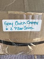Photo of a cardboard box labeled 'Gray Couch Covers w 2 Pillow Cases'