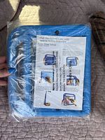 Blue shockproof iPad case in sealed plastic packaging with instructions for setup visible.