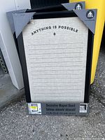 Front view of new decorative magnetic board with black frame and inspirational phrase 'Anything is Possible' at top. Shows protective corner guards and label with dimensions.