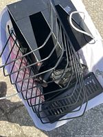 Photo showing a collection of black metal office organizers including file holders, paper trays, and stationery holders from a top angle in natural light.