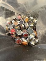 Plastic bag filled with multiple small round containers of various colored Scentsy fragrance wax testers viewed from above.
