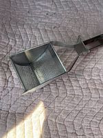 Top view of a square-shaped stainless steel kitchen sifter bowl with perforated bottom for flour sifting.