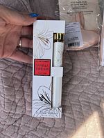 Photo showing a hand holding a new boxed Vanilla Dream For Her Eau de Parfum by Pour Femme, white box with gold floral design and red label, containing a 10ml spray bottle inside.