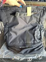 Front side view of the large black Beyond Yoga backpack showing the front zippered pocket with the brand name and drawstring closure.