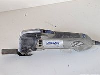 Side view of Dremel Multi-Max MM30 with blade attached, showing tool condition and dust wear.