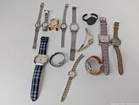Lot of 13 assorted watches including metal mesh bands, leather and fabric straps, and metal link bracelets arranged on white background.
