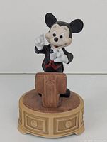 Front view of the Mickey Mouse conductor figurine showing the character in black conductor outfit with red vest, standing behind the podium on a tan base.