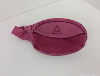 Front view of small pink Reebok hip pack with mesh detailing and Reebok logo.