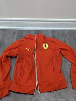 Front view of bright red Puma Ferrari jacket with visible logos and full zipper.