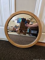 Front view of the round mirror showing the wooden frame and reflective surface.