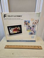Box of Fidelity Electronics digital picture frame showing branding and photos of families on the package