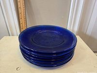 Stack of six blue ceramic plates with textured circular pattern and glossy finish.