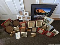 Photo of assorted picture frames showing various sizes and styles arranged on floor against wall and door