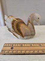 Side view of the carved onyx swan with a ruler for size reference showing about 4 inches.