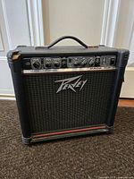 Front and left side view of the Peavey Rage 158 amplifier showing the chip on top left corner and control panel.