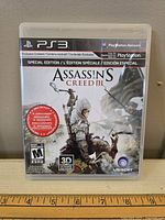 Front cover of PlayStation 3 Assassin's Creed III Special Edition game case showing game title, artwork, rating, exclusive content info, and Ubisoft branding.