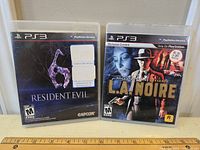 Photo of two PS3 game cases: Resident Evil 6 and L.A. Noire, showing front covers.
