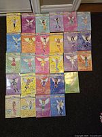 Top view of 27 Rainbow Magic books arranged in rows, showing colorful covers with various fairy illustrations and titles.