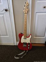 Full front view of red Peavey Reactor guitar and strap on floor