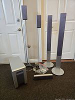 Full view of the six-piece Sony surround speaker system arranged on carpeted floor showing tall tower speakers, surround speakers, center speaker and subwoofer.