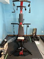 Front view of Bowflex PR3000 home gym showing bench, pulleys, cables and foam leg rollers