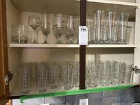 Shelves showing various types of glassware including wine, water, beer, and everyday glasses.