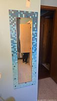 Full view of the rectangular wall mirror showing the reflective surface and blue tile border.