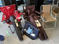 Six canvas folding chairs with brown carrying bags, one metal frame woven folding chair, and one blue Columbia thermal bag on carpeted floor.