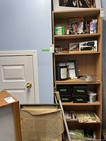 Wood shelving unit with assorted photography and art supplies, partially full boxes of negative film, Dremel electric engraver, magazines and framing wires