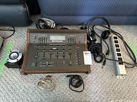 Overall view of all items included: Pyramid PR-5700 stereo mixer equalizer with wooden sides, Realistic super tweeter speaker, Koss headphones, cords, and power strip arranged on floor.