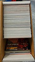 Top-down view of a large quantity of trading cards stacked inside a box.