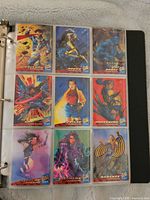 Photo of binder page showing front side of 9 different X-Men trading cards including Cyclops, Rogue, Beast, Wolverine.