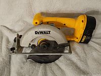 Side view of yellow DeWalt cordless circular saw showing blade guard, handle, and attached battery.