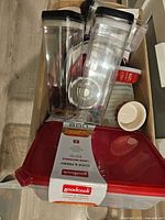 Photo showing Goodcook large rectangular Click & Fresh food storage container with red lid, label intact, and two tall clear containers with black lids behind it along with small white bowls.