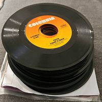 Stack of assorted 45 RPM vinyl records with Columbia label 'Toto Takin' It Back' visible on top record.