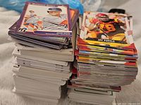Two large stacks of assorted sports cards showing baseball cards featuring Juan Soto and football cards showing Jay Tufele.