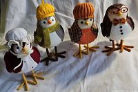 Four Target Featherly Friends owl figurines posed on white cloth, showing full front view of each item