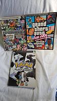 Photo showing the three video game guides: Pokedex Pokemon Black Version, Pokemon Black & White 2, and Grand Theft Auto Vice City official strategy guide.
