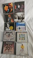Photo showing a mix of ten CDs including Metallica live album, Neil Diamond, Fleetwood Mac, Frank Sinatra, and others.