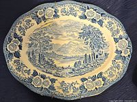 Oval ceramic platter with blue and white scenic design of Scottish lochs, floral border, and textured rim, shown from a top angle