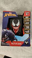 Photo of the Venom themed RC Flip Car in original packaging showing black car with Venom design and box details.