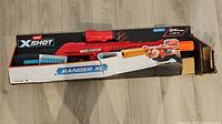 Photo of the Zuru XShot Ranger X2 toy blaster packaged in box with some damage present on the box showing torn edges and dents.
