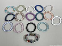 Overview of 15 stretch bracelets with round beads in a variety of natural stones in colors including light blue, white, pink, dark blue, purple, black, peach, turquoise, and multicolor.