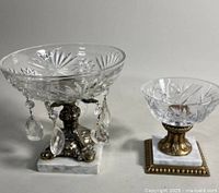 Front view showing two cut crystal compote bowls on brass pedestals with white marble bases, one with hanging crystal drops