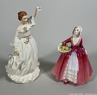 Two Royal Doulton porcelain figurines side by side, Au Revoir and Janet, both standing on a grey surface.