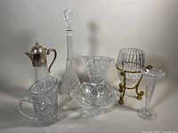 Photo showing the full lot containing the decanter, claret jug, pitcher, bud vases and small bowl arranged together against a neutral background.